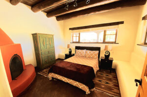 A cozy Southwestern-style bedroom featuring a queen-sized bed with patterned bedding in soft tones and a plush dark throw blanket.
