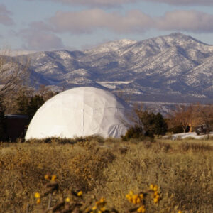 Chi Center Dome set against a stunning backdrop of snow-capped mountains and desert flora, offering a unique space for healing and meditation retreats.