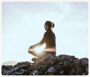 A serene image of a person meditating on a rocky hilltop at sunrise, radiating calm and mindfulness