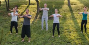 A group of people doing Qigong in a park.