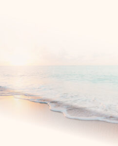 A serene beach scene with gentle waves washing onto the shore under a soft, pastel-hued sky at sunrise or sunset.