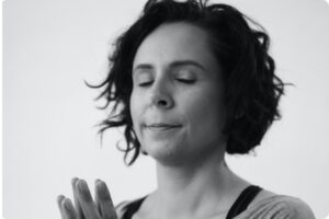 A woman holding her hands together in Qigong practice.