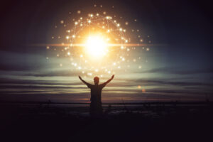 Silhouette of a person raising arms towards a glowing sphere of interconnected light nodes, symbolizing energy, connection, and spiritual awakening against a serene sunset background.