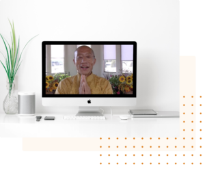 Master Mingtong Gu appearing on a laptop screen in a bright, minimalistic setting with a white background and green plant, symbolizing simplicity, focus, and online learning in Wisdom Healing Qigong.
