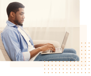 A young man wearing a casual blue shirt sits comfortably on a couch, focused on typing on his laptop in a bright and minimalistic living room, symbolizing productivity and online learning.