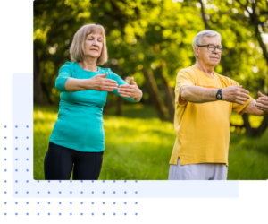Older couple practicing Qigong outdoors in a serene park, focusing on gentle movements and mindfulness to enhance health and well-being.