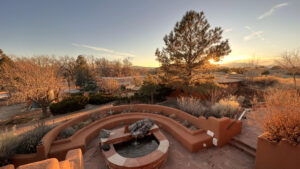 serene sunset view of The Chi Center's peaceful patio, featuring a terraced fountain, vibrant vegetation, and stunning distant mountains in Galisteo, New Mexico.