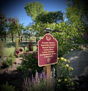 Scenic garden view with vibrant green trees, clear blue sky, and a decorative outdoor lantern creating a peaceful natural ambiance.