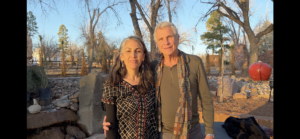 Outdoor portrait of an individual standing among bare winter trees, with a clear blue sky in the background, evoking a serene and natural atmosphere.