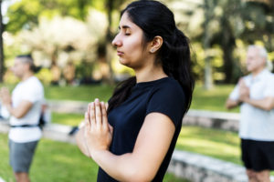 Serene woman meditating outdoors, surrounded by soft greenery, embodying mindfulness and inner peace.