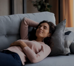 Relaxed woman resting peacefully on a comfortable couch, enjoying a moment of tranquility in a cozy home setting.