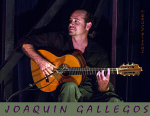 Joaquin Gallegos, a flamenco guitarist, performing on stage with a classical guitar under warm lighting, wearing a black shirt and pants, with his name written at the bottom of the image.