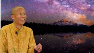 Master Mingtong Gu smiling warmly in a golden traditional robe, set against a breathtaking backdrop of a star-filled night sky and a mountain reflected in a serene lake, symbolizing wisdom and cosmic connection.