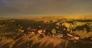 An aerial view of The Chi Center at sunset, showcasing the expansive landscape, adobe-style buildings, and natural beauty of the surrounding New Mexico terrain.