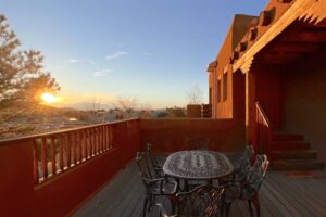 Sunset view from Pueblo #9 featuring a spacious outdoor patio with an elegant wrought iron dining table, wooden railings, and stunning mountain scenery in the background.