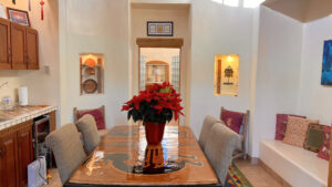 Serene dining area with handcrafted wooden table, red poinsettia centerpiece, and cozy seating adorned with decorative pillows at The Serenity Center.