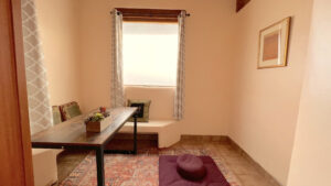 Cozy window corner at The Serenity Center featuring soft curtains, warm lighting, and a framed artwork on the wall.