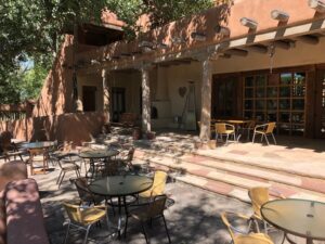 Charming view of The Dining Patio at The Chi Center, featuring shaded seating, rustic adobe architecture, and a serene atmosphere perfect for enjoying meals and conversations in nature.