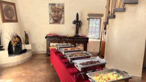 Buffet setup with chafing dishes of food in a serene room featuring Buddha artwork, a fireplace, and decorative elements.
