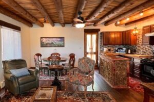 Interior of The Zia Apartment featuring a cozy open-concept design with wooden ceiling beams, a fully equipped kitchen, a dining area, and a living space with stylish furniture and Southwestern decor.