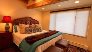 Tranquil Moonlight Room in Zia #1 at The Chi Center, showcasing a luxurious bed with vibrant pillows and a handcrafted wooden headboard, warm lighting, and large windows for a relaxing ambiance.
