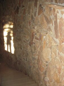 Stone wall staircase illuminated by sunlight casting intriguing shadows, creating a rustic and mysterious atmosphere.