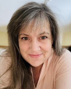 Close-up of Gillian Gonda's hair and forehead, set against a softly lit indoor background.