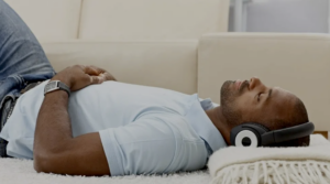 Close-up of a person's hand resting on their lap, seated on a light-colored sofa in a calm, modern indoor setting.
