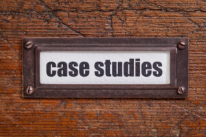 Close-up of a vintage metal label holder on a wooden surface, containing the text 'case studies' on a white background.