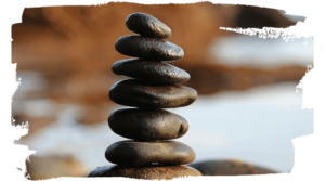 "Close-up of a balanced stack of smooth black stones on a reflective surface, symbolizing harmony, balance, and mindfulness in a natural setting.