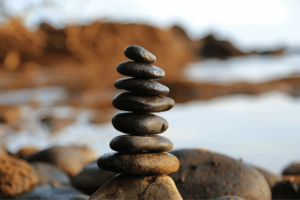 Close-up of a balanced stack of smooth black stones on a rocky shoreline.