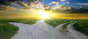 A serene landscape at sunrise with a forked dirt path leading towards the radiant horizon, symbolizing choices, new beginnings, and the journey of self-discovery for the Spring 2024 Mini-Retreat Series.