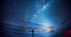 A lone figure stands under a vast night sky, illuminated by a breathtaking display of the Milky Way. The scene is rich in blues and purples, reflecting off what appears to be a vast body of water, enhancing the sense of solitude and the expansive nature of pure consciousness as explored through Wisdom Healing Qigong.
