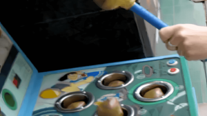 Close-up of a person playing a classic arcade 'Whack-a-Mole' game, with a mallet poised to strike as figures pop up from holes. The image captures focus, quick reaction, and playful engagement, symbolizing active participation and resilience in the Masterclass Play environment.