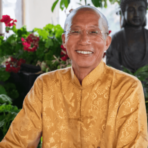 Master Mingtong Gu smiling warmly in a serene environment, wearing a traditional golden outfit, embodying the essence of Qigong and healing.