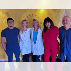 A group photo of the Santa Fe Soul Center team, standing together against a warmly lit, golden-hued wall with a textured, artistic design. The team members wear a mix of medical scrubs and white lab coats, symbolizing their dedication to holistic wellness and integrative health care. Their friendly smiles and relaxed postures reflect a welcoming, compassionate atmosphere at the center.