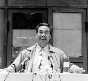 Dr. Pang Ming, founder of Zhineng Qigong, smiling while speaking at an event. A moment capturing wisdom, joy, and leadership in Qigong practice