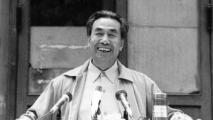 Dr. Pang Ming, founder of Zhineng Qigong, smiling while speaking at an event. A moment capturing wisdom, joy, and leadership in Qigong practice