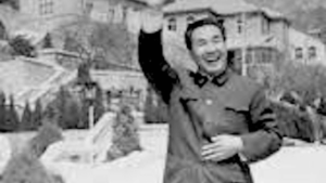 Dr. Pang Ming joyfully waving in an outdoor setting, surrounded by a traditional backdrop, embodying the essence and spirit of Qigong practice