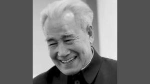 Black and white photograph of Dr. Pang smiling warmly, wearing a traditional Chinese jacket. His expression is joyful, with eyes gently closed in laughter, showing a deep sense of peace and happiness.