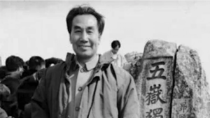 "Dr. Pang Ming standing outdoors beside a stone engraved with Chinese characters, capturing a moment of presence and connection to Qigong practice.