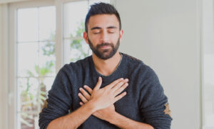Person practicing Wisdom Healing Qigong, with hands on the heart center and eyes closed, embodying peace, mindfulness, and self-healing.