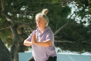 Woman practicing Qigong outdoors with hands in prayer position, as part of a 7 Weeks of Sound Healing focus, enhancing mindfulness and energy flow.