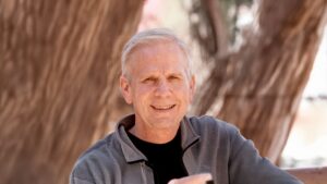 Portrait of Tom smiling outdoors against a natural background of trees