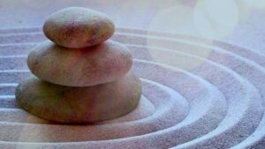 A tranquil arrangement of three smooth stones stacked in a Zen garden with concentric sand patterns, symbolizing balance, harmony, and mindfulness.